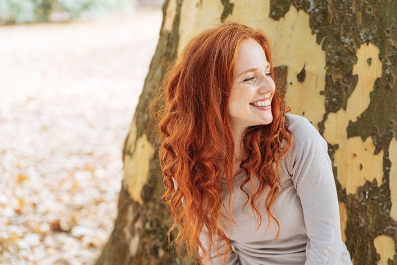 Smiling young woman in front of tree