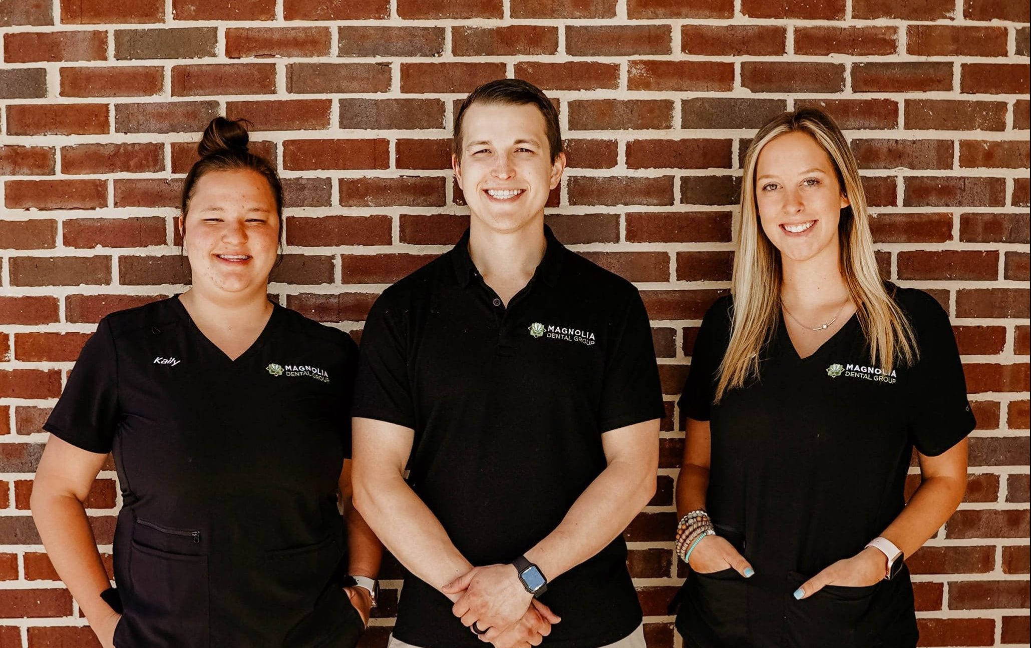 Magnolia team standing in front of a brick wall